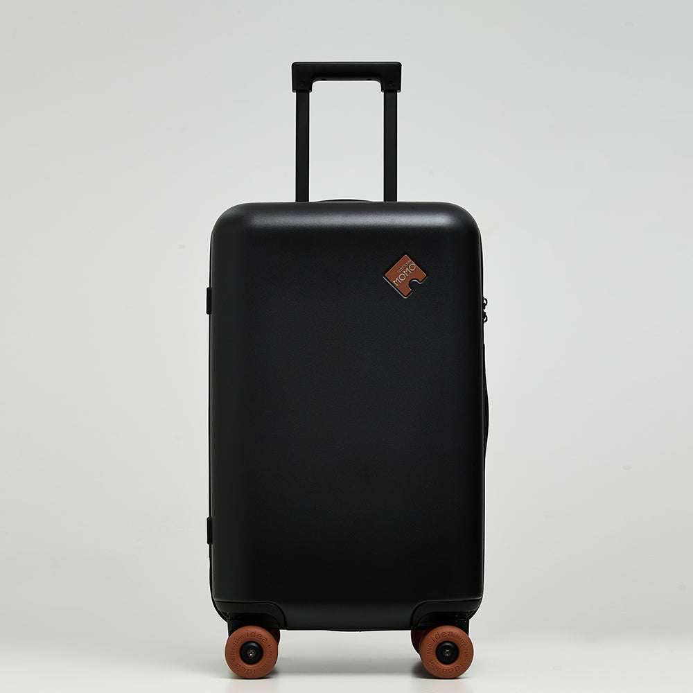 Front view of Lovetour black hardshell suitcase featuring caramel brown puzzle logo and matching 3" silent donut wheels